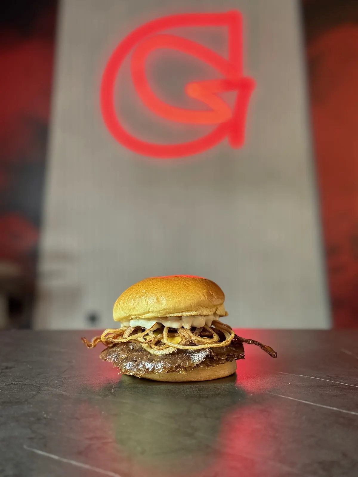 Hamburguesa servida junto al logotipo de GULA SUPREME