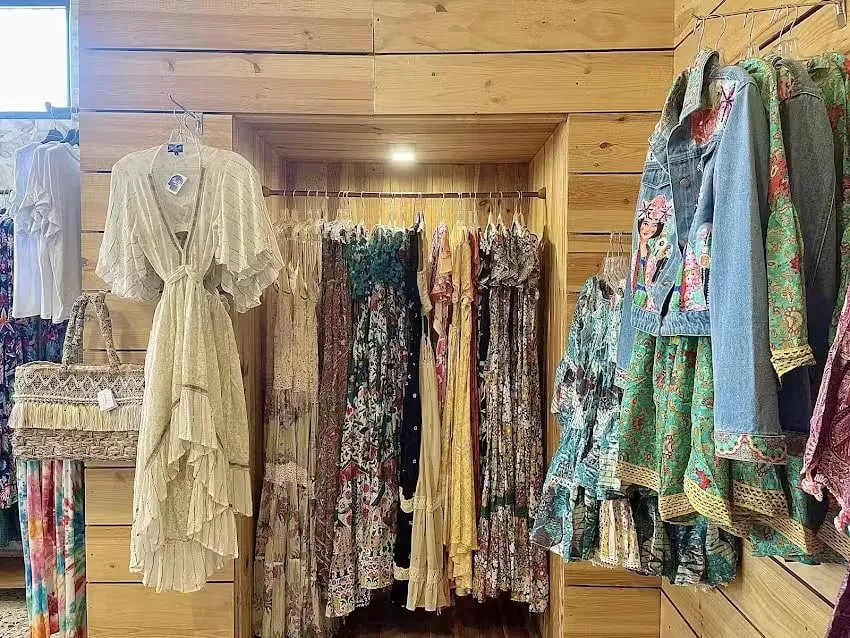 Interior de la tienda Cocco & Cocó con vestidos de estilo boho colgados en perchas sobre paredes de madera