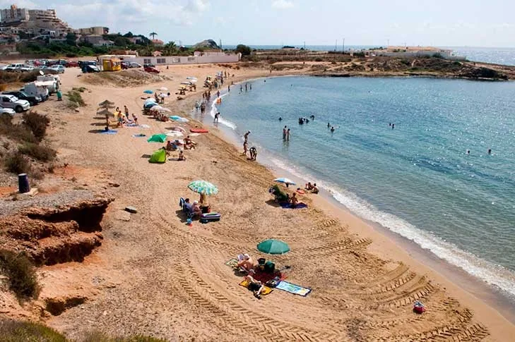 Bañistas y sombrillas de colores sobre la arena dorada de Cala Reona, en Cabo de Palos