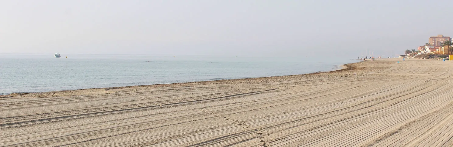 Arena amplia y rastrillada de Playa del Estacio con el Mediterráneo en calma a primera hora