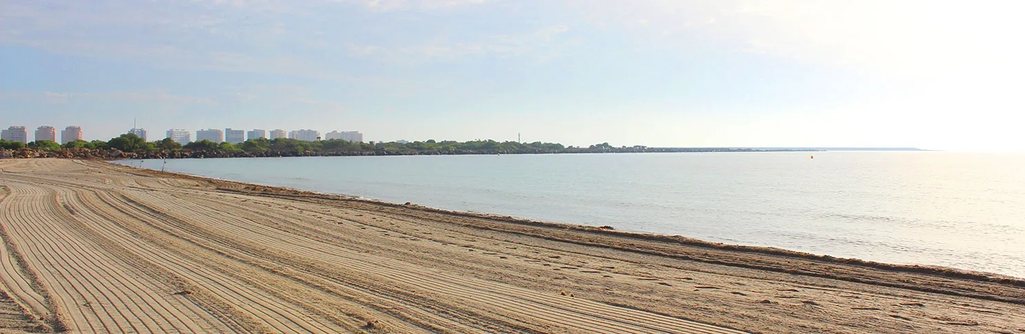 Playa del Estacio vacía con la arena peinada y la costa de La Manga perdiéndose al fondo