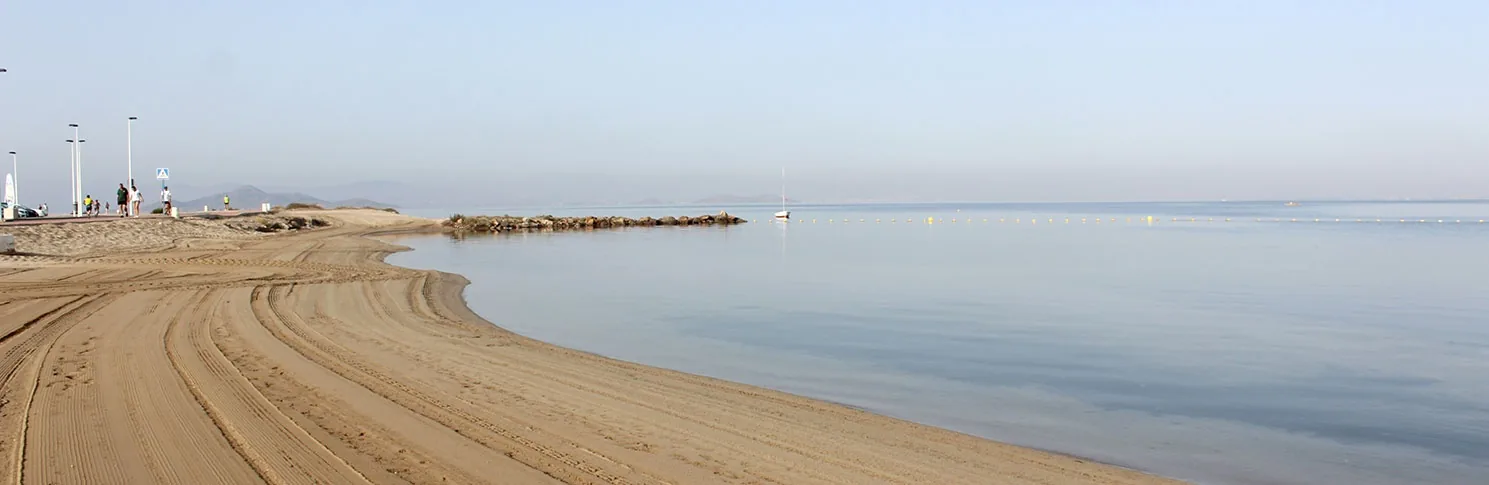 Orilla y espigón de Playa Mistral sobre las aguas sin oleaje del Mar Menor