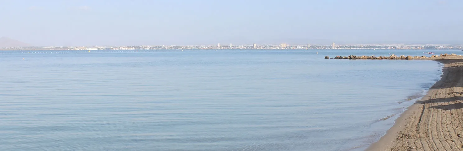 Aguas planas del Mar Menor en Playa La Veneziola, con la orilla de arena gruesa en primer plano