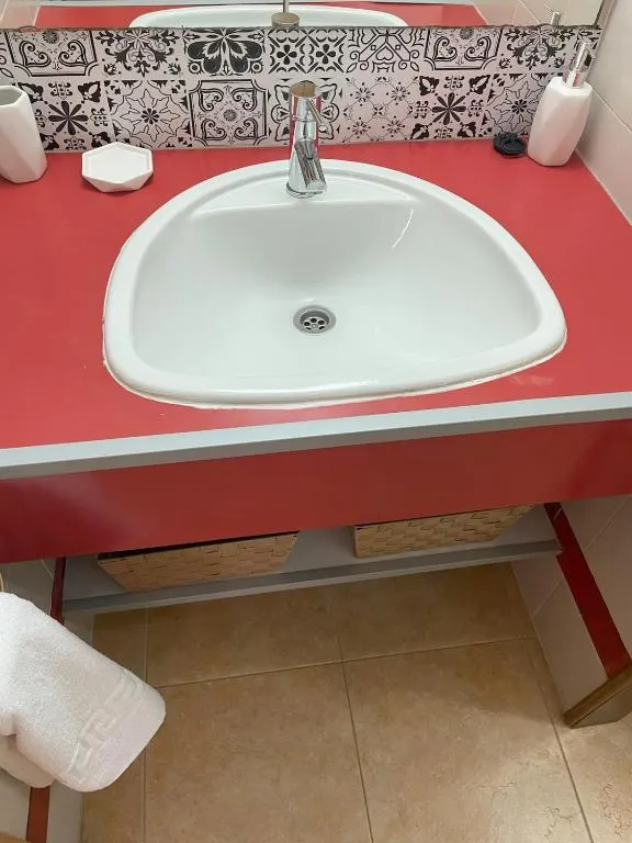Lavabo del baño del apartamento con encimera roja y azulejos decorados