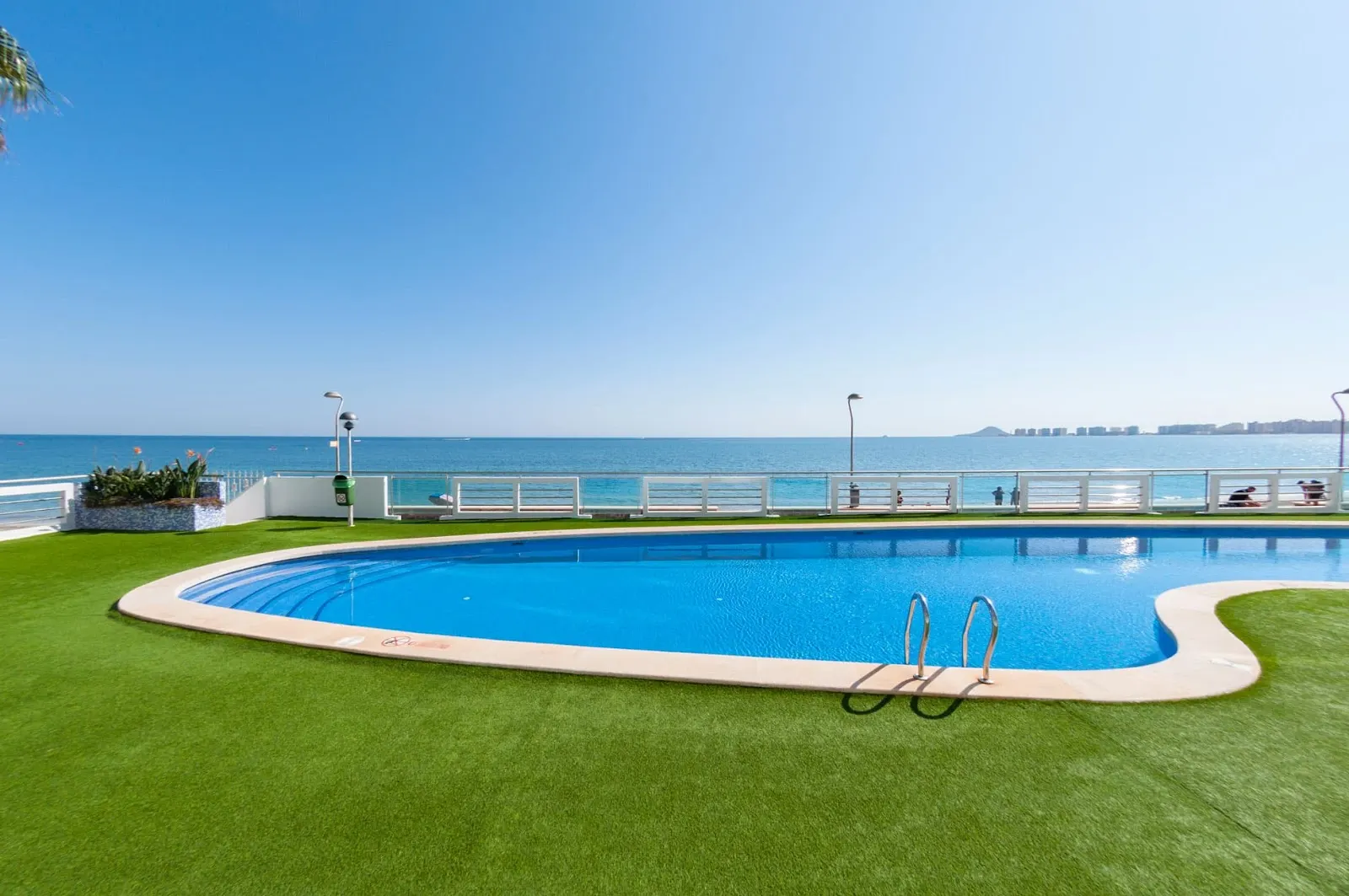 Piscina con césped artificial y vistas al mar en el apartamento Entre Dos Mares