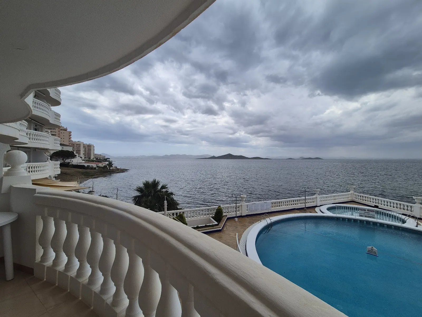 Vista de la piscina y el Mar Menor desde un balcón de Apartamentos Dominique