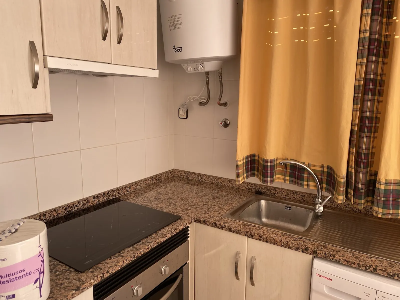 Cocina equipada con vitrocerámica y termo en un apartamento de Olympia Center