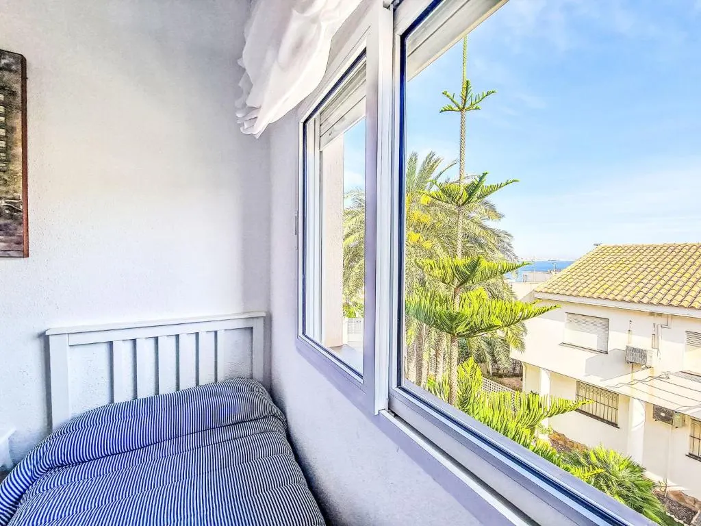 Dormitorio con vistas a los tejados y al mar en el apartamento La Galera
