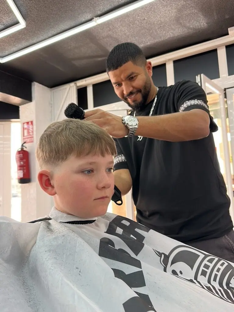 Barbero cortando el pelo a un niño en Issan The Black