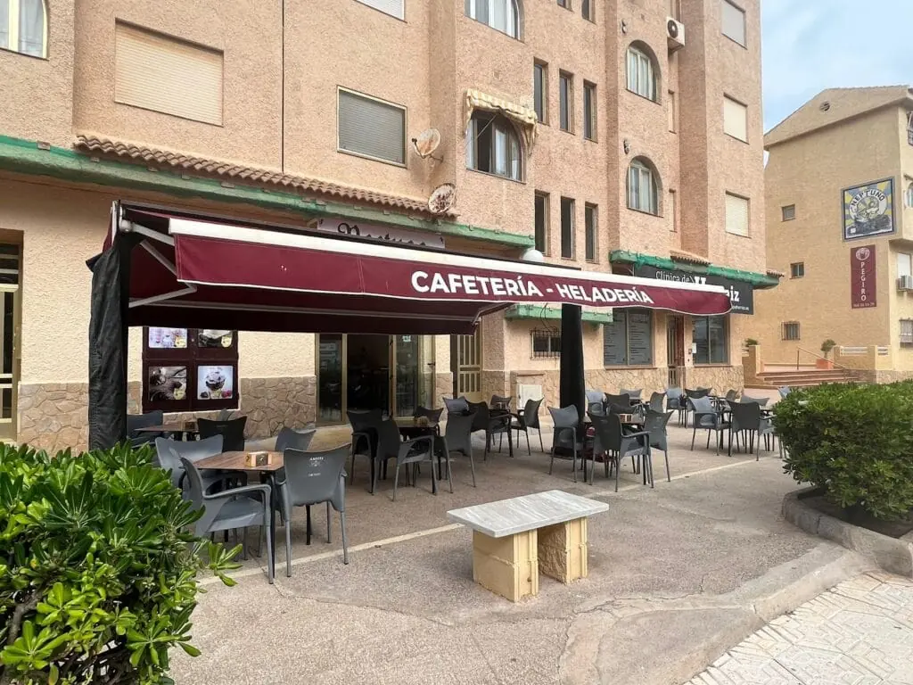 Terraza de Cafetería Heladería Neptuno bajo el toldo granate, km 7,5 de La Manga