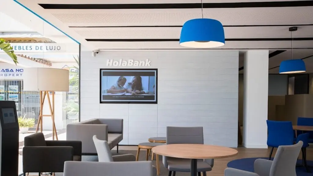 Sala de espera de la oficina CaixaBank con la marca HolaBank en la pared