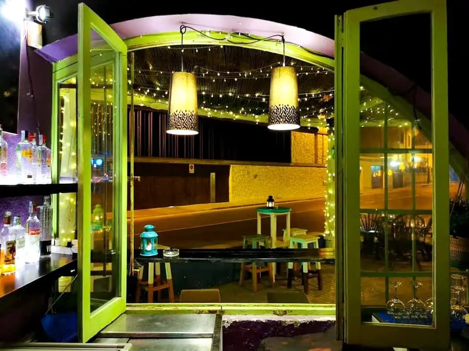 Entrada del bar Chinchorro con luces cálidas y mesas altas en el interior