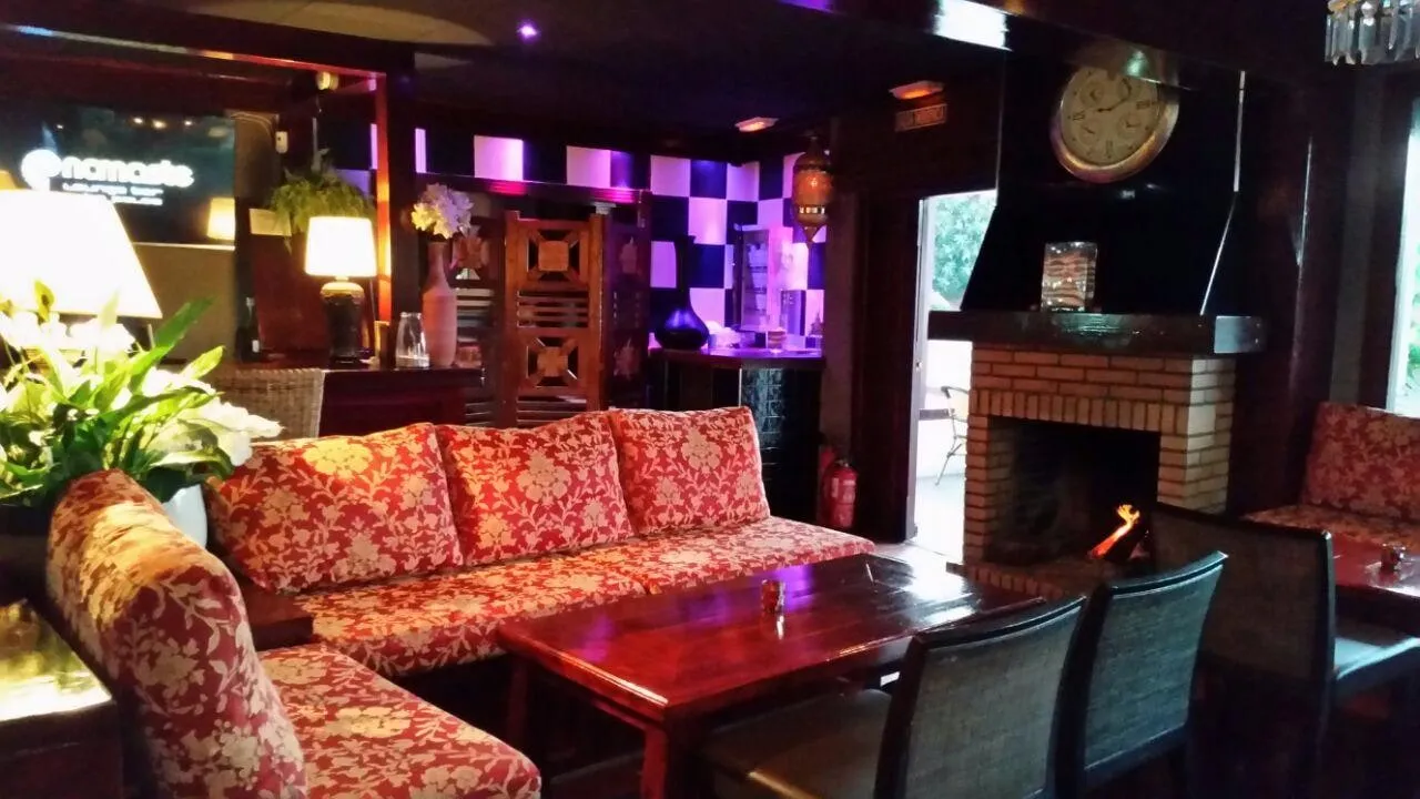 Interior de El Capitán con sofás rojos, chimenea encendida y ambiente de bar de copas