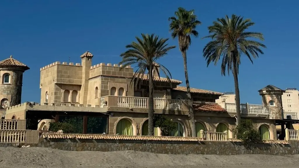 Vista general de El Castillo de La Manga con sus torres y palmeras, en primera línea de playa