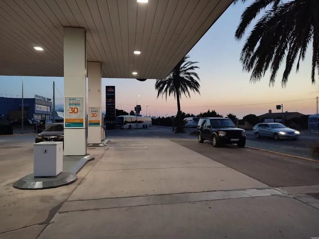 Surtidores de la Estación de Servicio Repsol al atardecer, con palmera junto al acceso