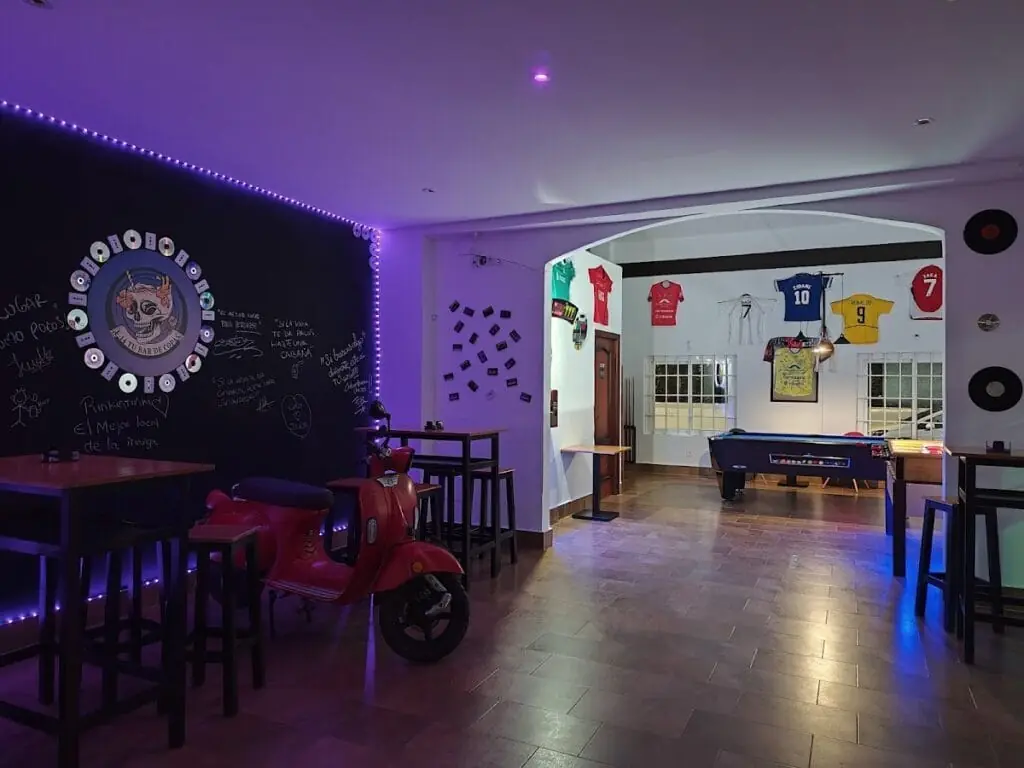 Sala interior de F-14 con moto vespa decorativa, mesas altas y mesa de billar al fondo