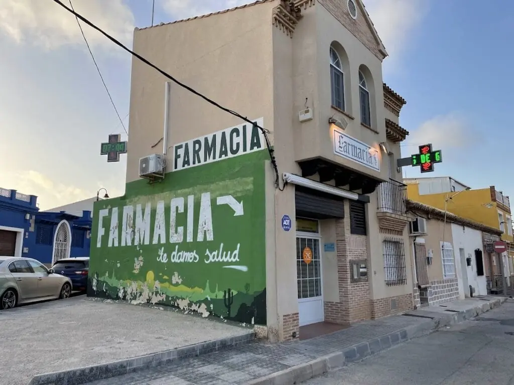 Fachada de Farmacia Cabo De Palos con el rótulo verde de farmacia, Calle Sirio