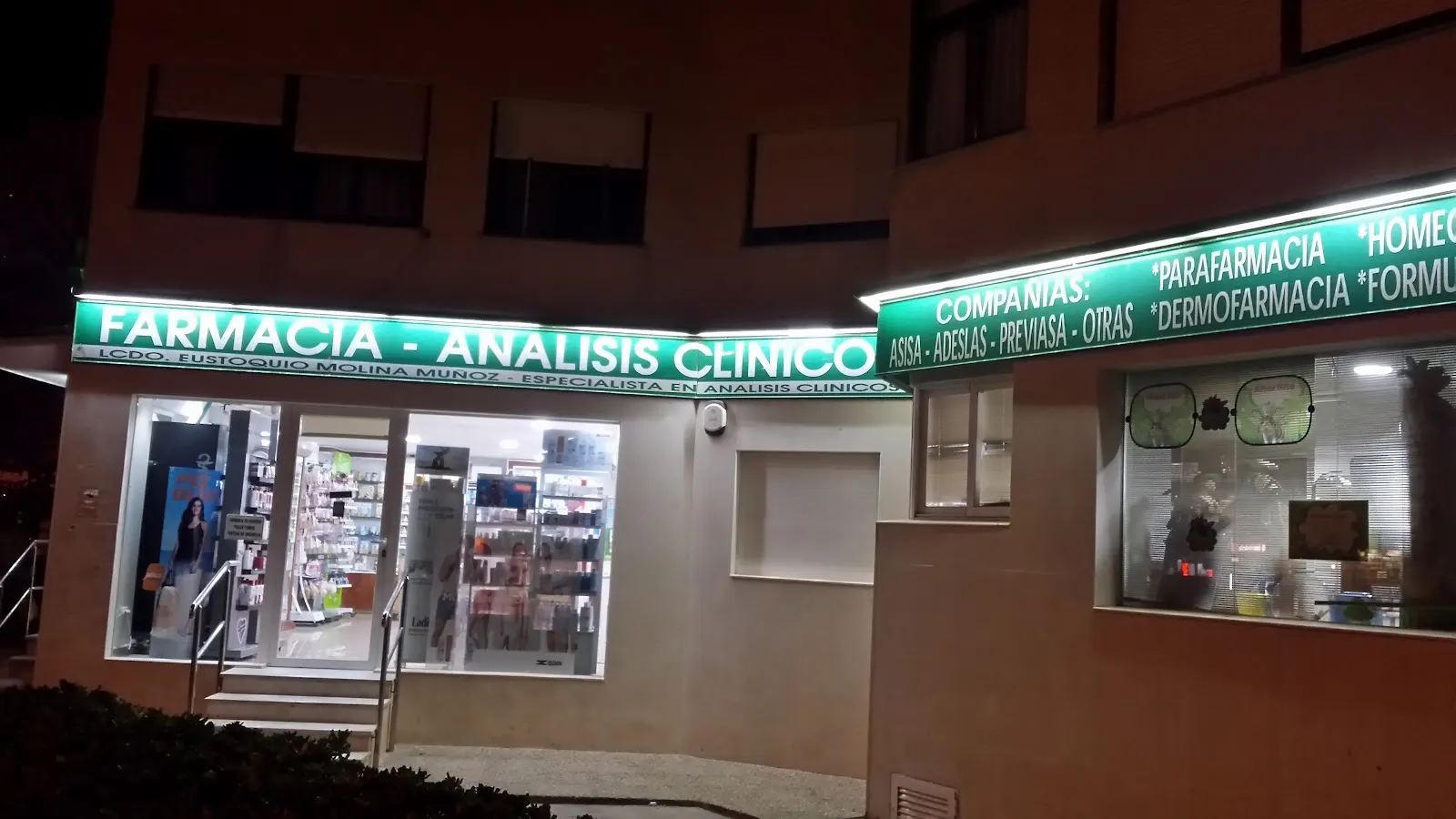 Fachada nocturna de Farmacia Plaza Bohemia con cartel de análisis clínicos