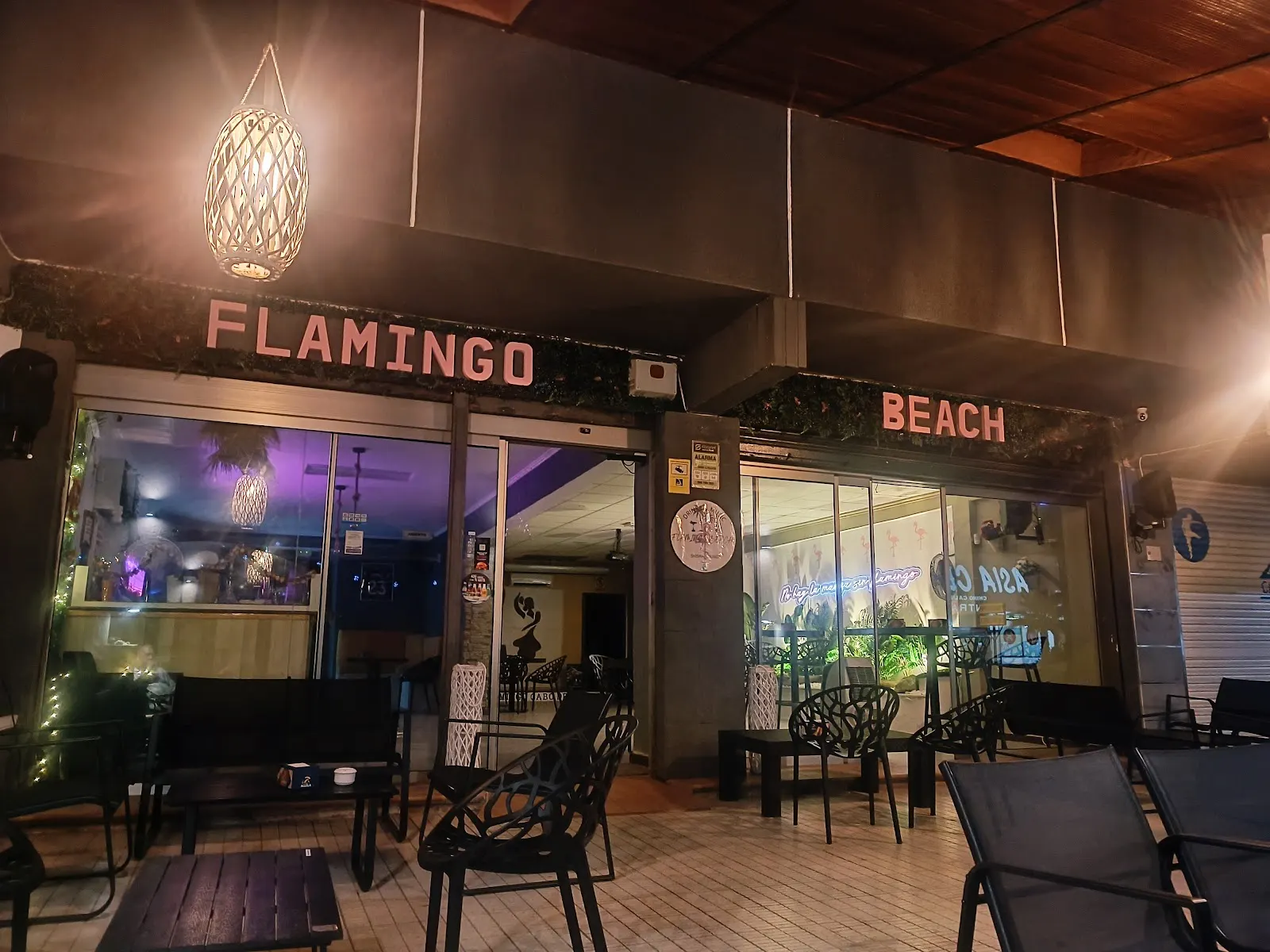 Fachada nocturna de Flamingo Beach con su terraza exterior