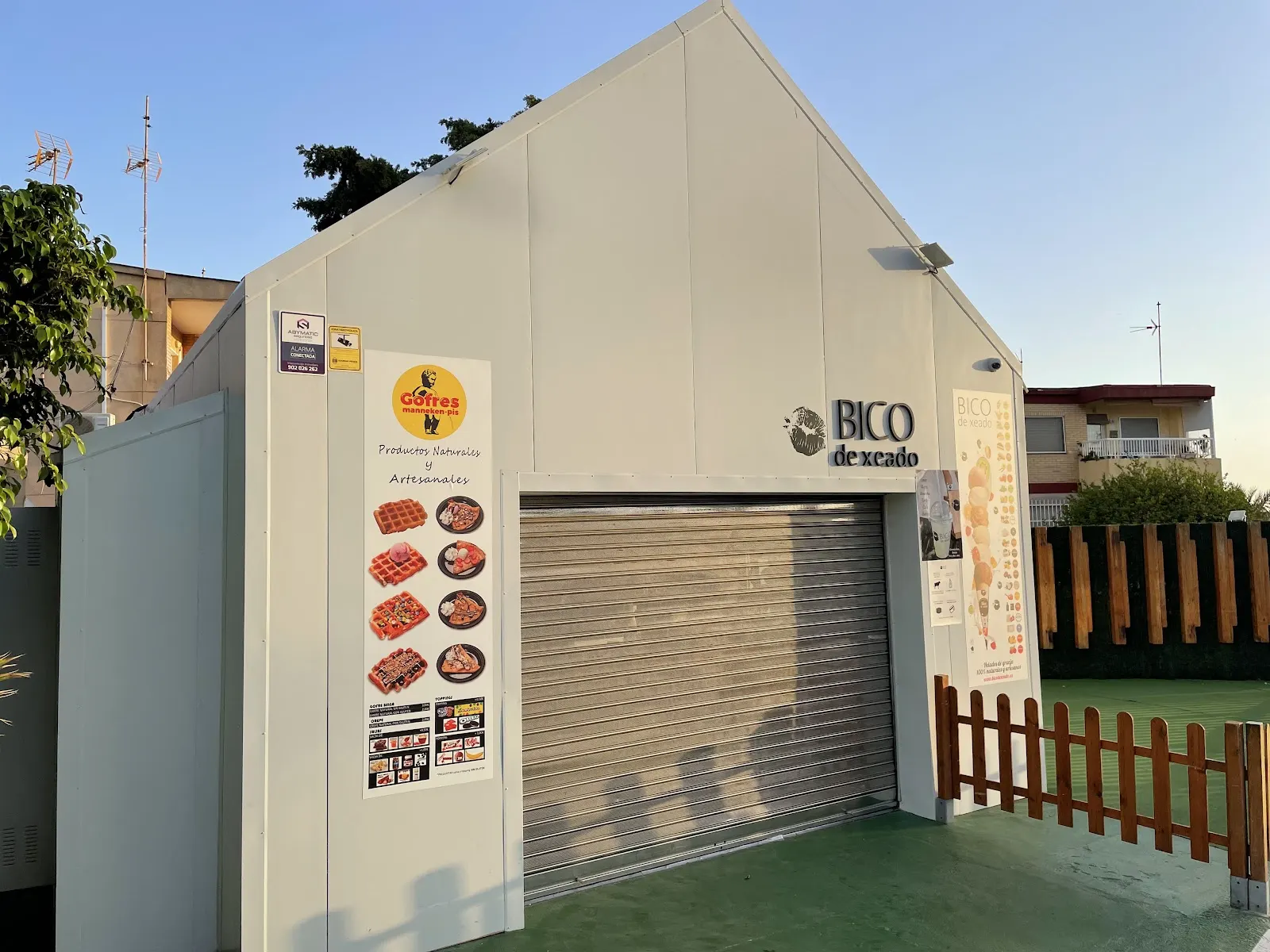 Entrada de la Heladería Bico de Xeado al atardecer, junto a una pista deportiva