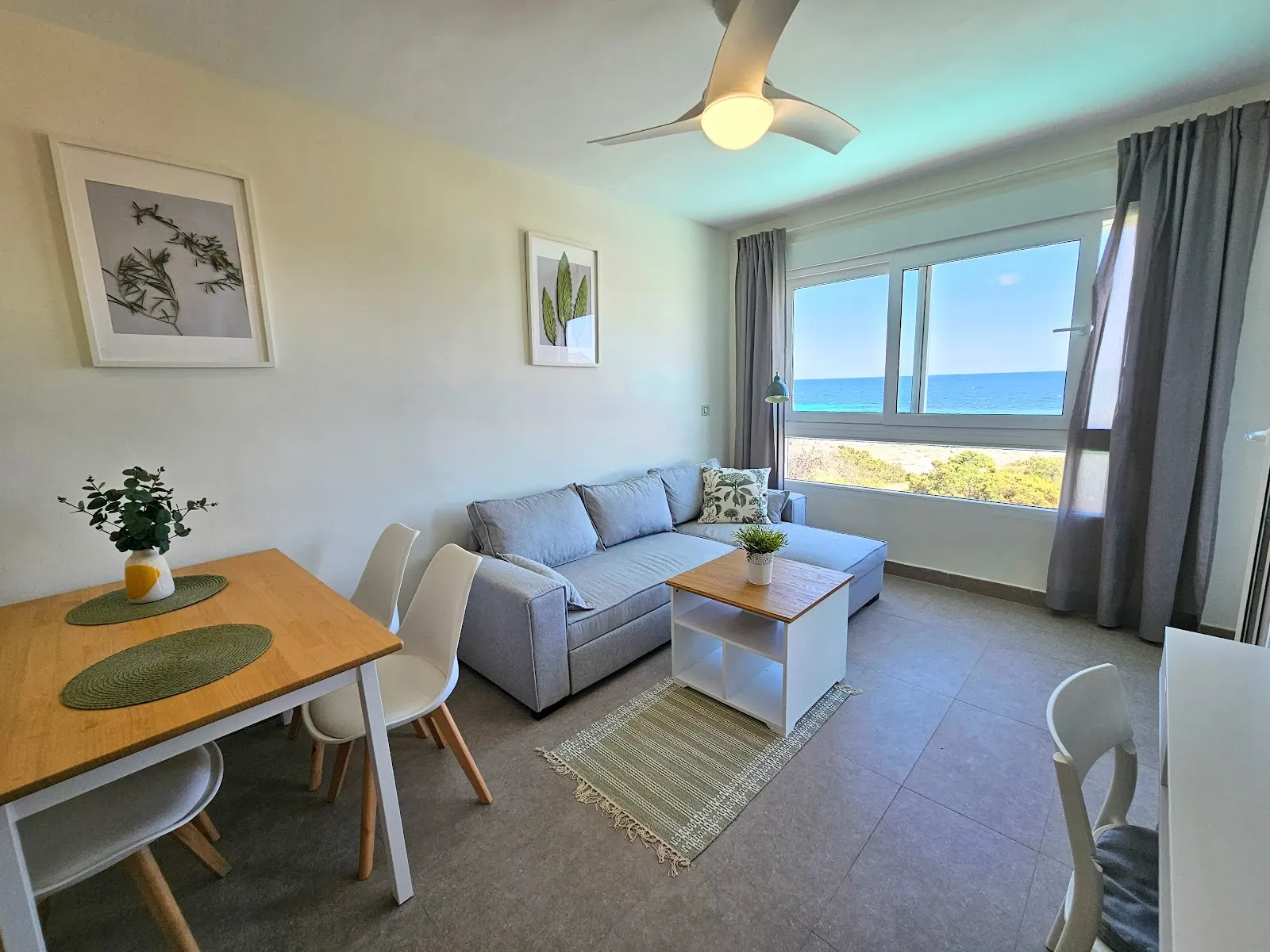 Comedor y salón del apartamento con ventilador de techo y vistas al Mediterráneo
