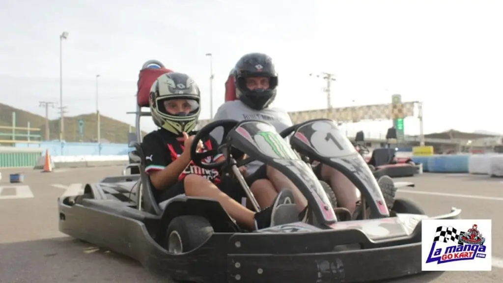 Dos niños con casco en un kart biplaza en el circuito de La Manga Gokart