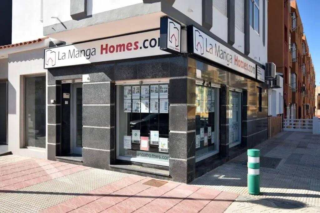 Fachada de la oficina de La Manga Homes, con anuncios de propiedades en el escaparate