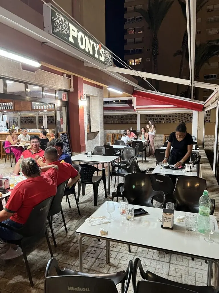 Terraza de Los Pony's con clientes por la noche en Plaza Bohemia