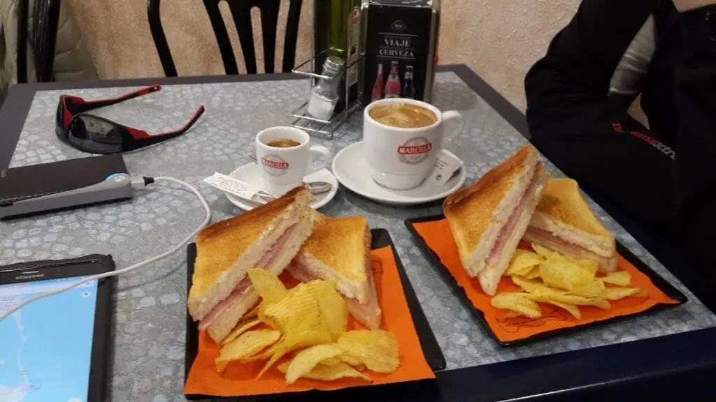 Montaditos de jamón y queso con dos cafés servidos en una mesa