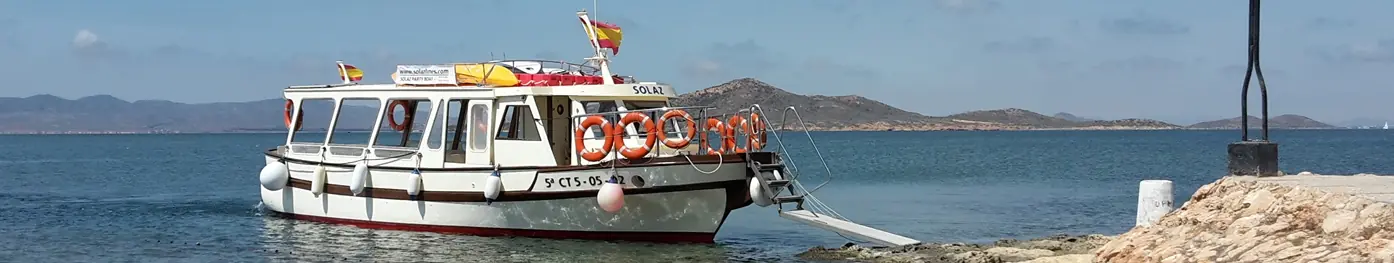 El barco Solaz amarrado junto a la orilla con la sierra al fondo