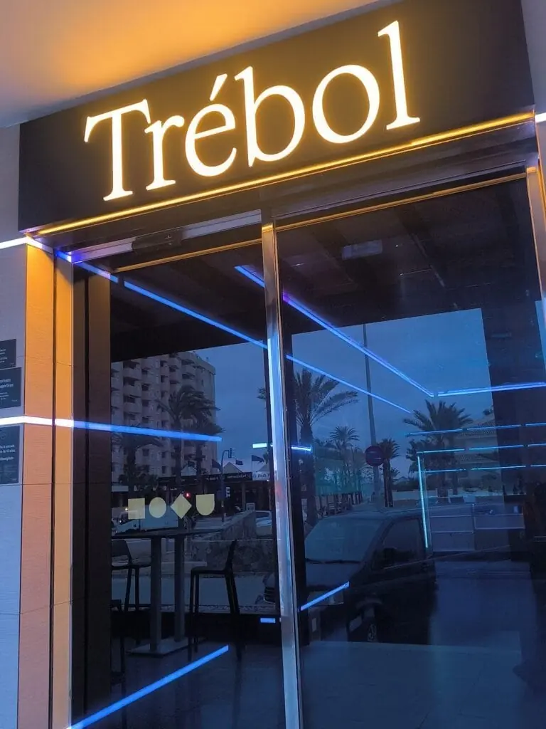 Entrada de Sportbar Trébol con el rótulo luminoso al atardecer
