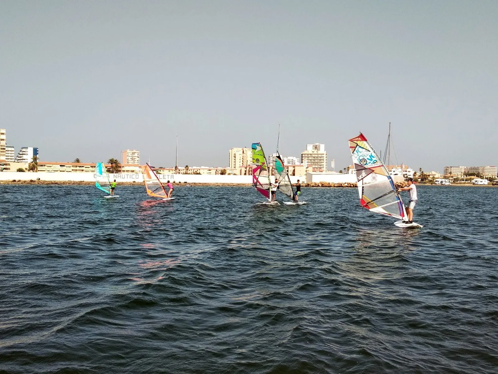 Alumnos de windsurf de Tatowind Sailing School frente al Club Náutico La Isleta