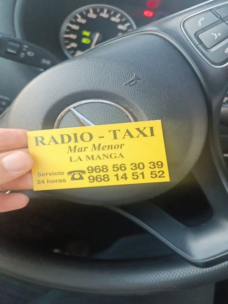 Tarjeta de Radio Taxi Mar Menor con sus teléfonos, sobre el volante de un taxi