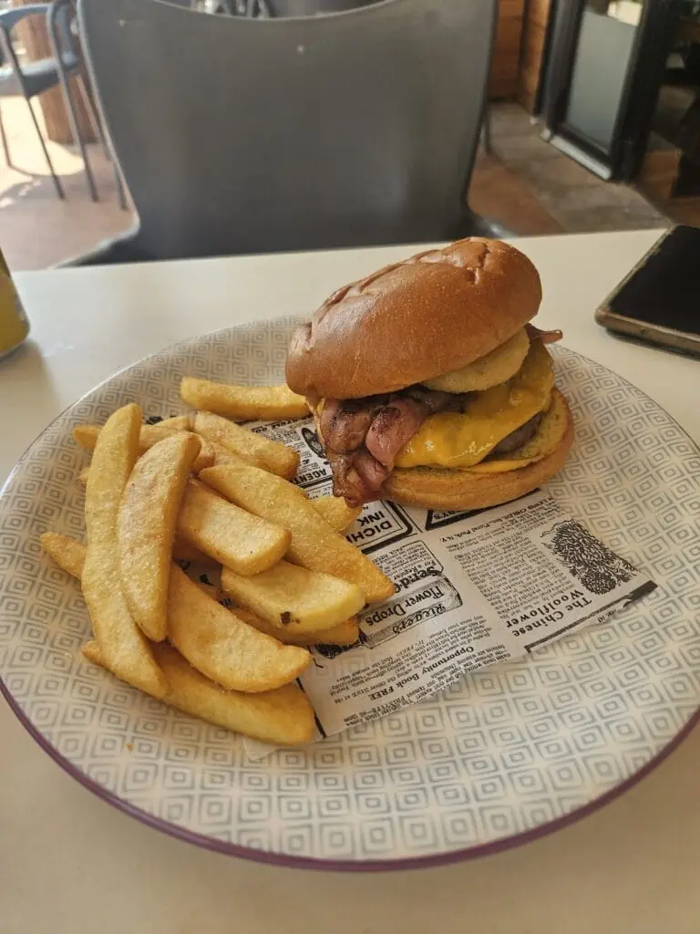 Hamburguesa con patatas fritas servida en la terraza de Teckel Bar