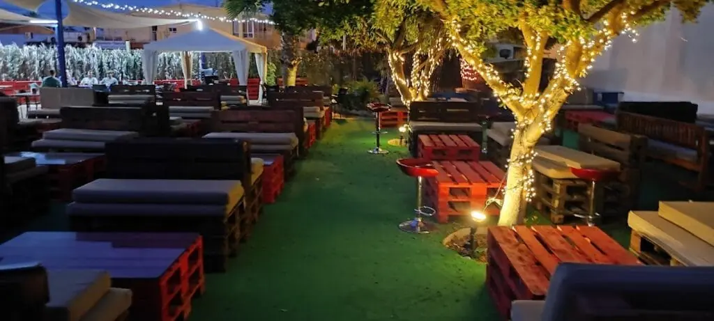 Terraza nocturna de Vaya Vaya con mobiliario de palés e iluminación cálida, Calle Yuca