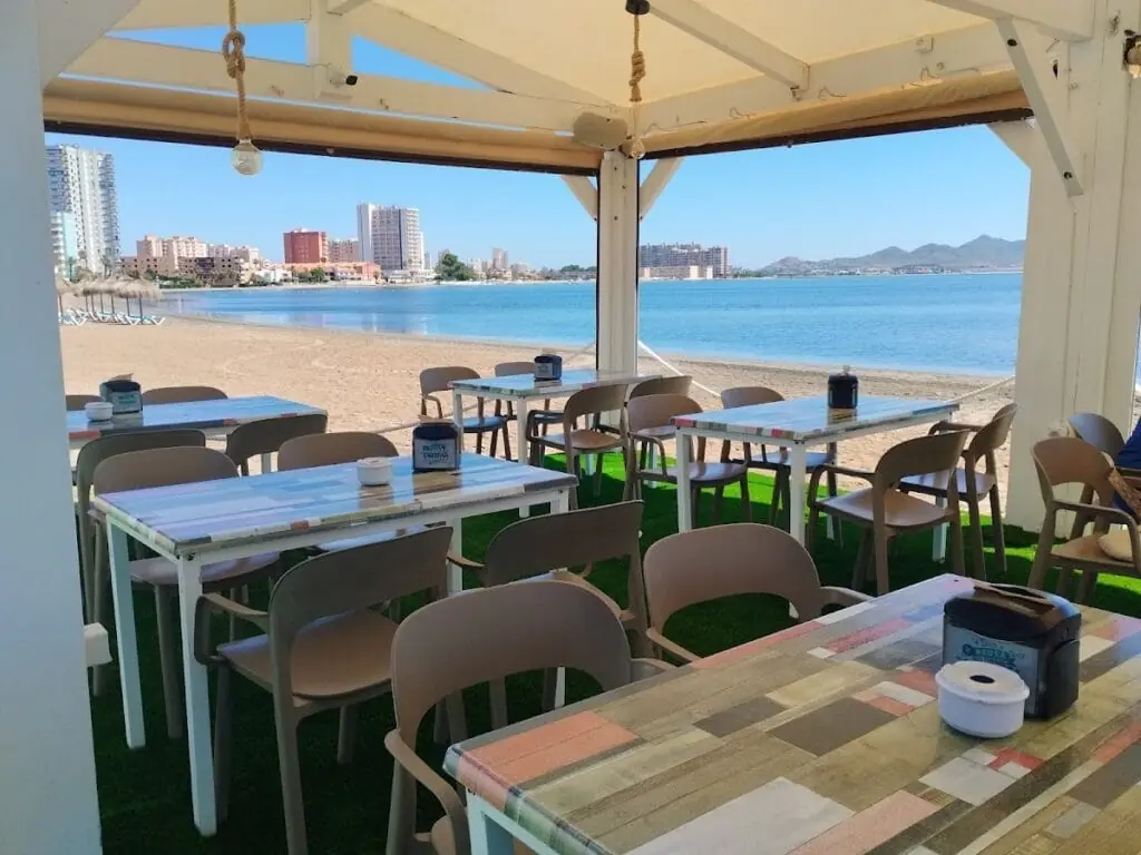 Terraza de Umai Beach con mesas sobre la arena y vistas al Mar Menor