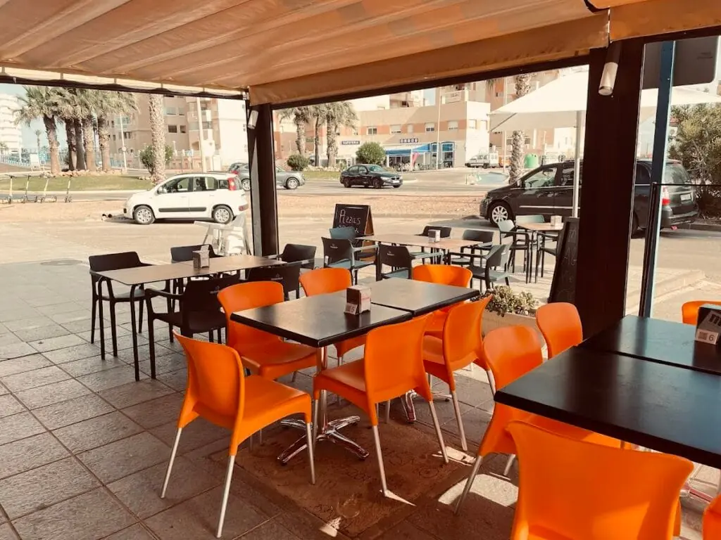 Terraza con mesas y sillas naranjas de Va & Ven