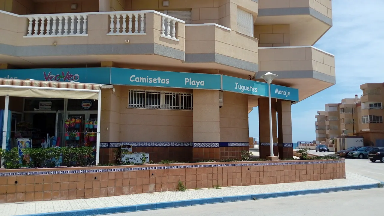 Fachada del quiosco Veo-Veo en la Urbanización Castillo de Mar, con rótulo de camisetas y artículos de playa
