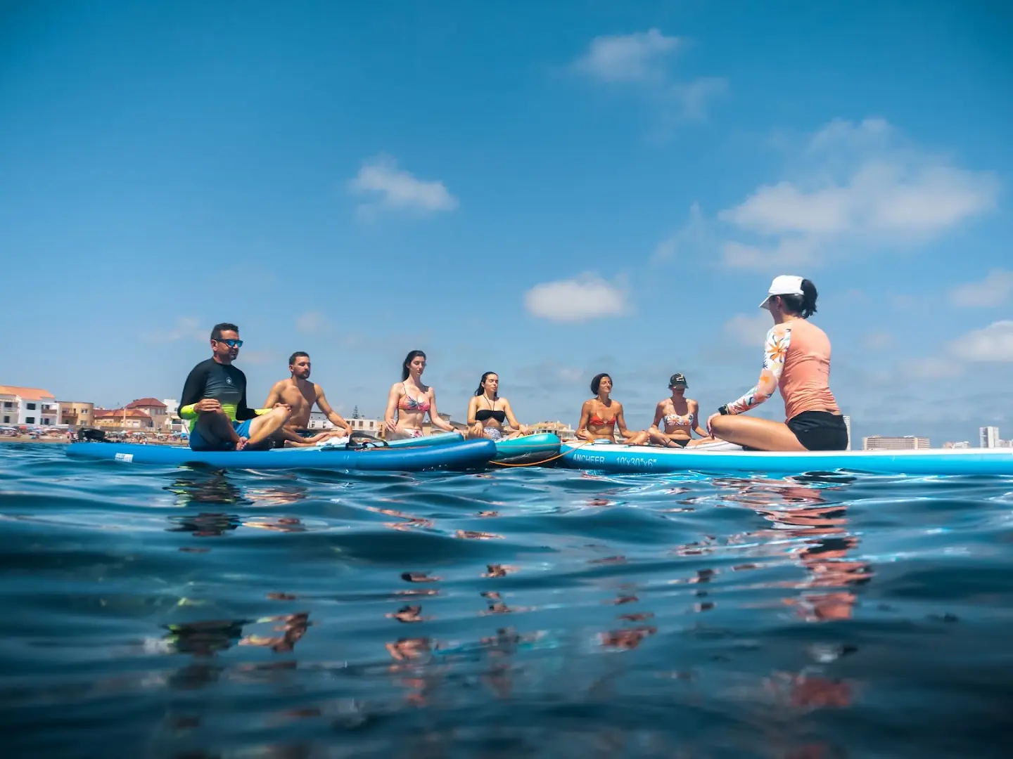 Grupo practicando SUP yoga sobre tablas de paddle surf en el mar de Cabo de Palos con WIMBI