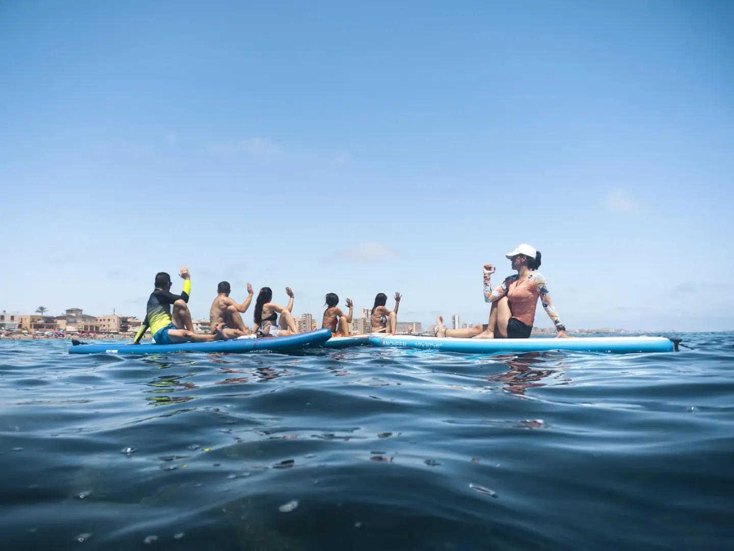 Grupo de alumnos de Wimbi sentados en tablas de paddle surf en el Mar Menor